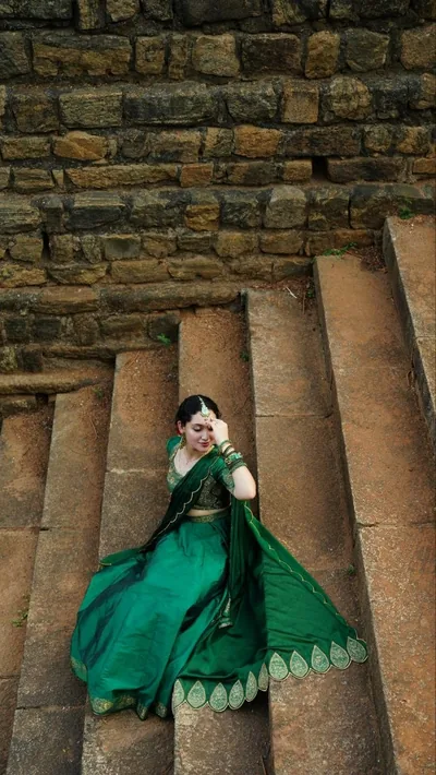 Green lehenga with a scalloped dupatta on old stone steps